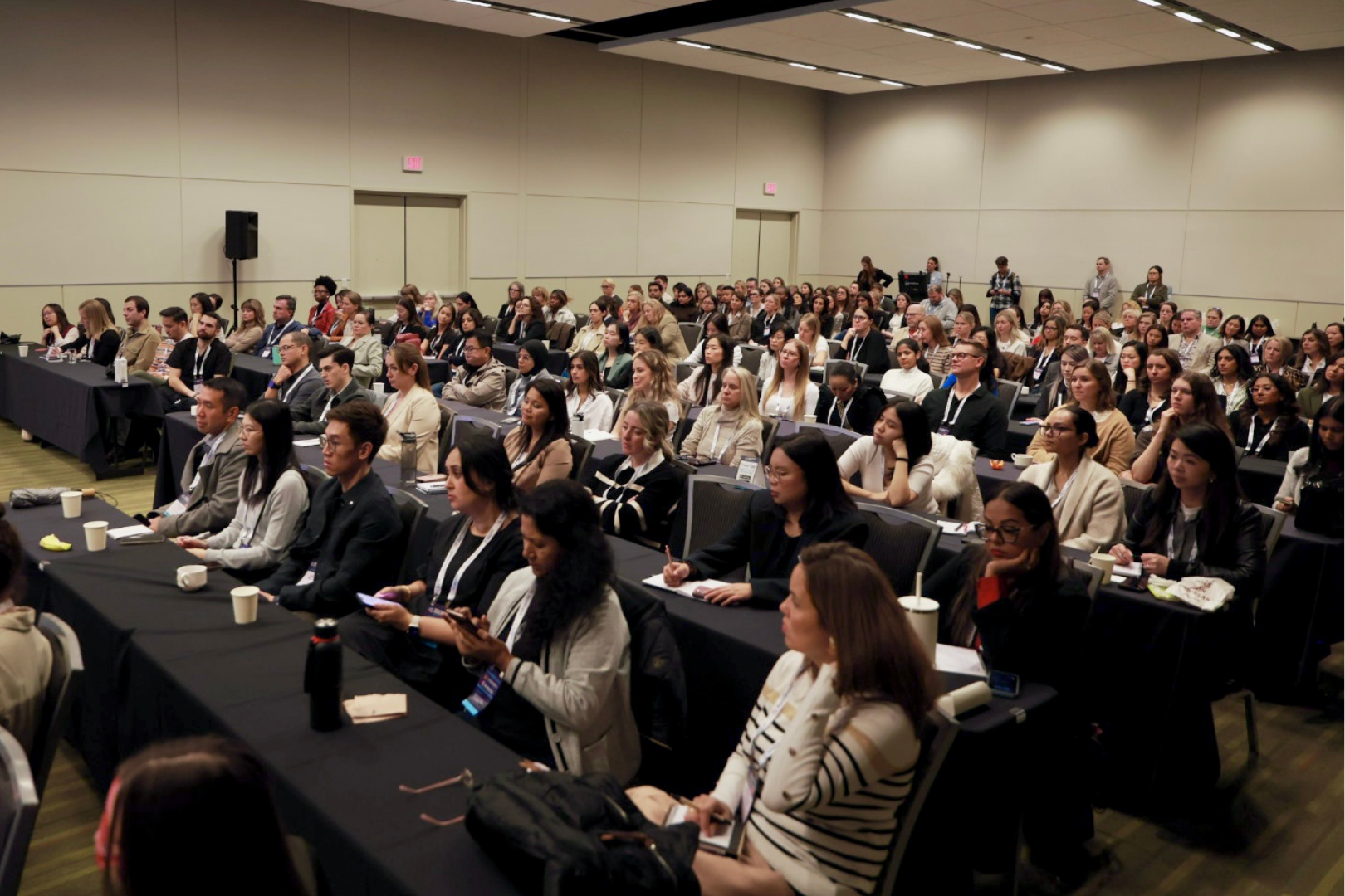 a crowd of people at a conference, listening to a speaker