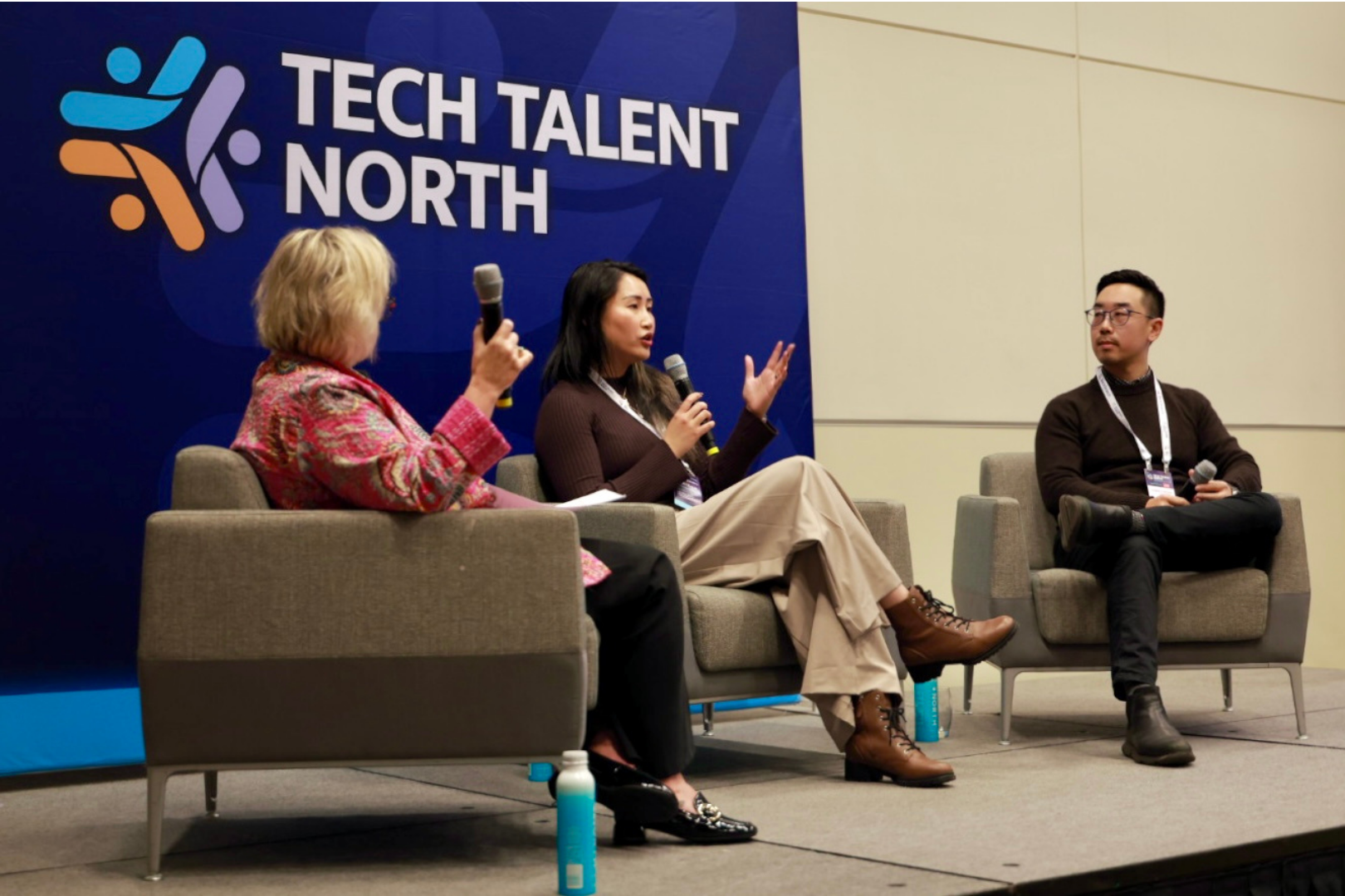 three people sitting on stage at Tech Talent North, presenting as panelists