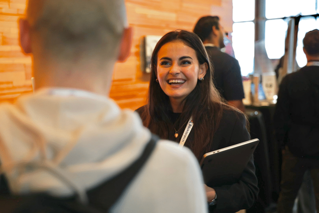 A woman smiling, while talking to someone.