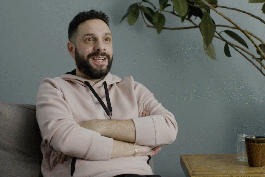 Man sitting with arms crossed, smiling.