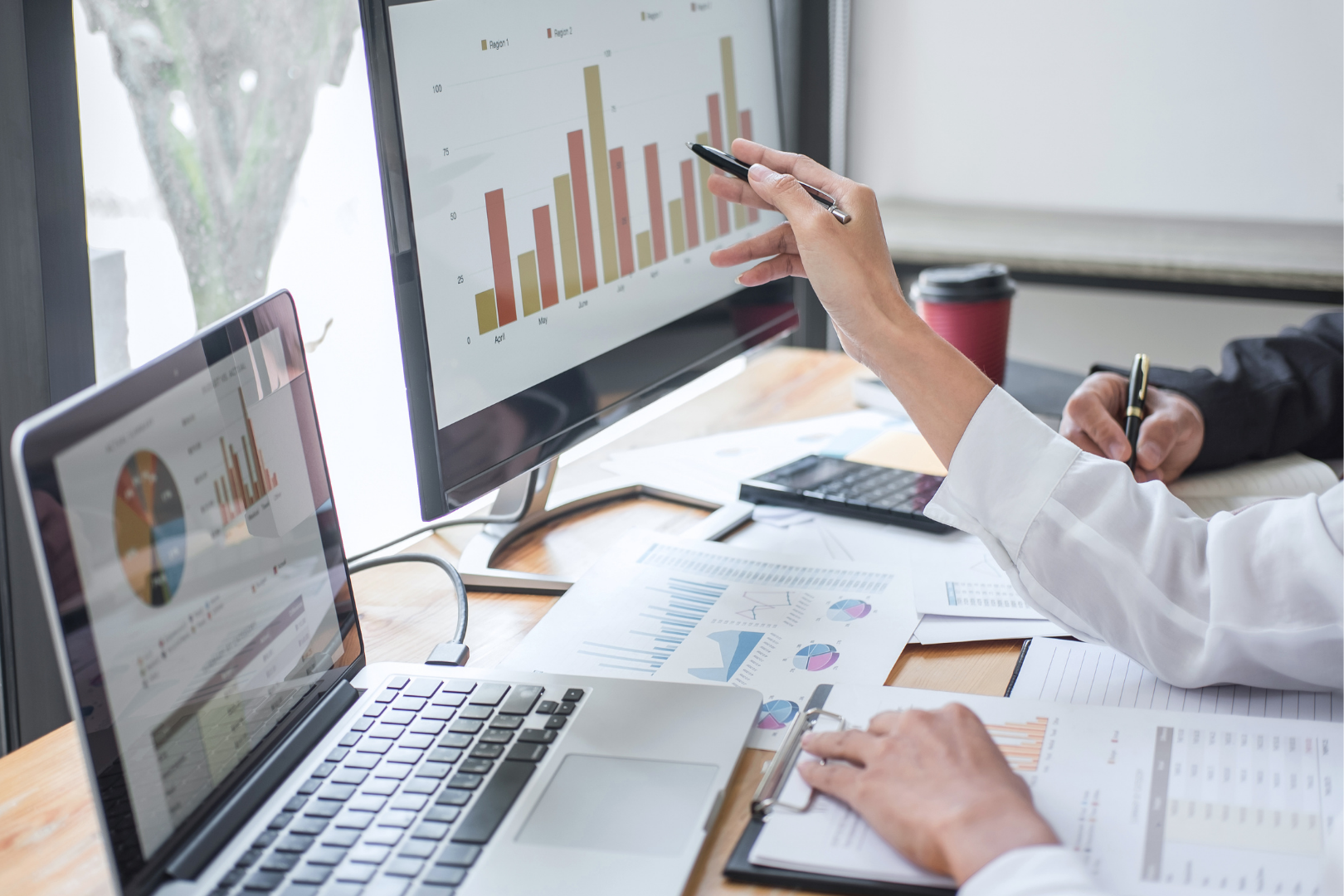 hands pointing at a computer screen, graphics on the screen